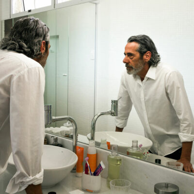 middle-aged man looking at himself in mirror