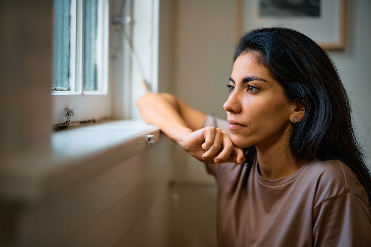 Emotional woman looking out window in deep thought